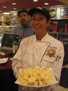 Lynn Battels displaying the Grafton Village Farms Classic Reserve Cheddar with David Hall behind her.