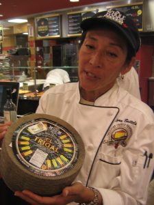 Lynn Battels with a wheel of cheese.